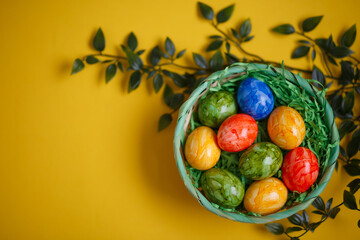 Easter card. Flat lay composition with easter eggs in a basket on yellow background.