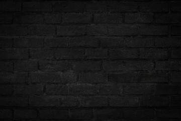 Old vintage black color grunge brick wall textured background with vignette at the edge of picture and an empty space for text.