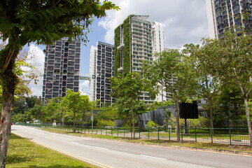 Fototapeta na wymiar View at the street at Singapore with tall buildings in green grass and leaves, a lot of trees, empty road, ecological life, concept of modern life.
