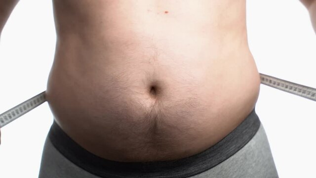 Close up video of a chubby man measuring his waist