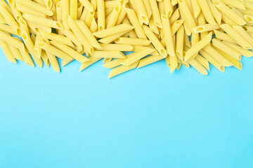Frame from penne type of pasta on cheerful blue background with empty space for text.