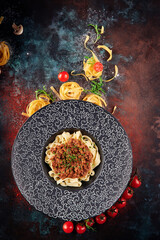 Pasta pappardelle with beef ragout sauce in a black plate. Oxidized background. For the menu. top view