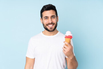 Caucasian man with a cornet ice cream isolated on blue background smiling a lot