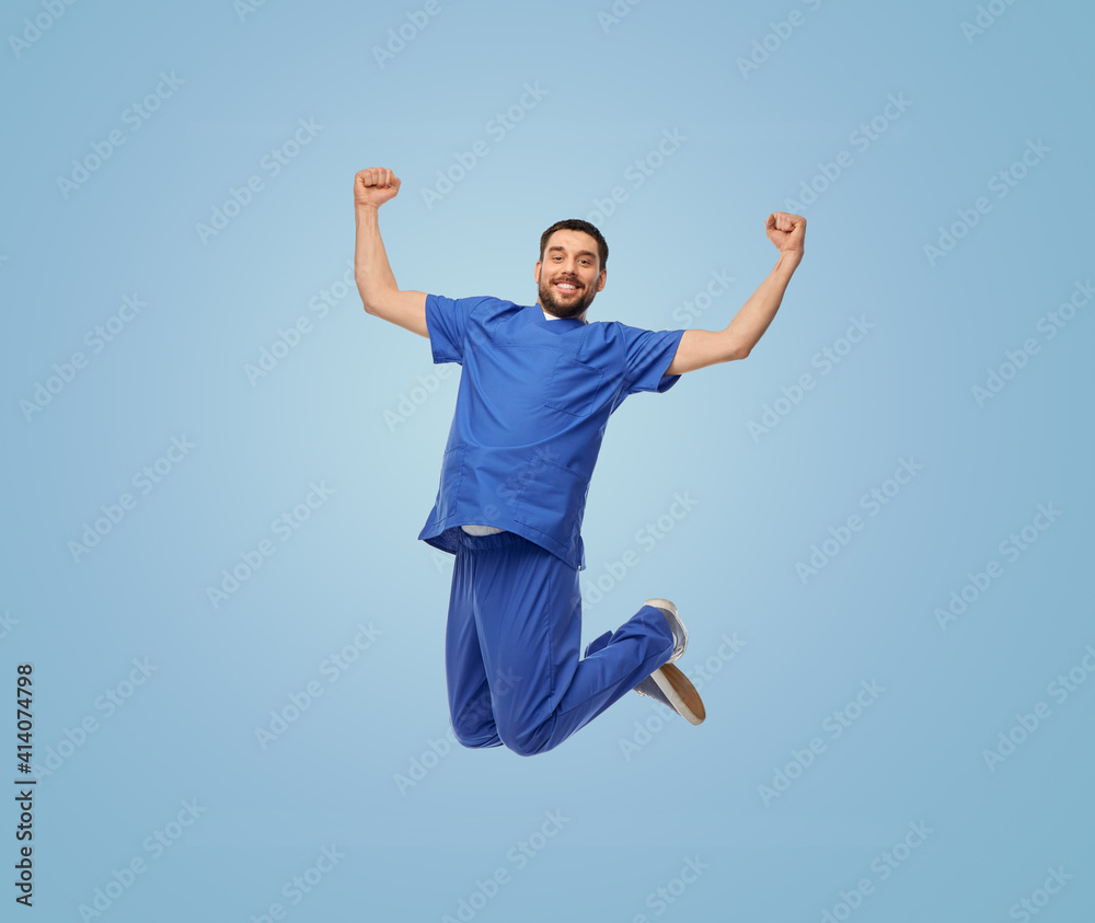 Wall mural healthcare, profession and medicine concept - happy smiling doctor or male nurse in uniform jumping in air over blue background