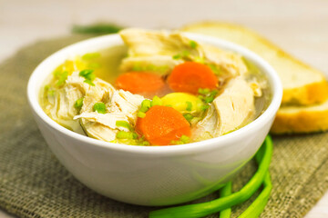 Chicken Soup stew broth and vegetables in white bowl on old rustic wooden cutting board