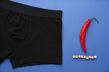 Men's underwear, chili pepper and word Impotency on blue background, flat lay