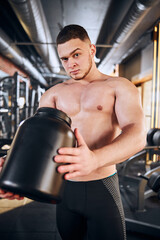 Fototapeta na wymiar Young bodybuilder using sport nutrition during training