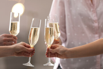 People clinking glasses of champagne against blurred background, closeup