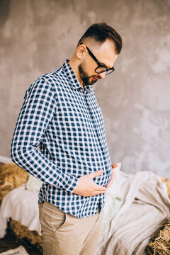 A man wearing glasses depicts a pregnancy with a belly