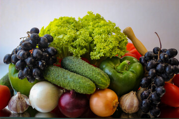 Prepare for a wonderful vegetarian lunch. Washed bell peppers, green cucumbers, onions, garlic, grapes and lettuce leaves