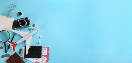Flat lay composition with toy airplane and travel items on light blue background. Space for text