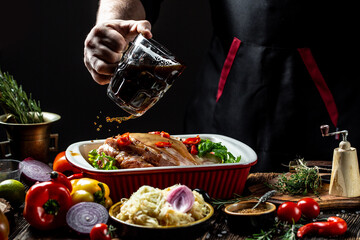 Roasted knuckle of pork with the addition of beer. Oktovber recipe for festival. banner, menu recipe. a chef hands preparing bavarian pork knuckle