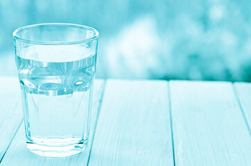 A glass with pure clear melt water stands on a white table