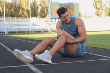 Fototapeta premium Man in sportswear having knee problems at stadium