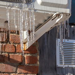 Very beautiful transparent icicles hanging structures of the house. Icicles falling danger concept.