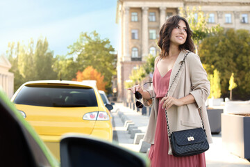 Young woman with stylish black bag and sunglasses on city street