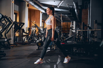 Fototapeta na wymiar Cheerful young woman enjoying workout with weights