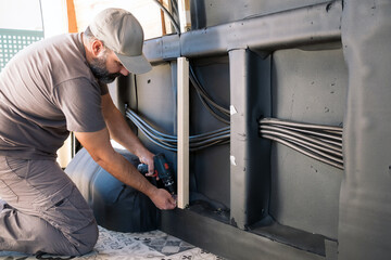 Bearded man screwing with a cordless drill. Construction of a camper van.