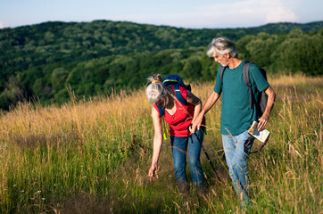 Active senior couple with backpacks hiking in nature.