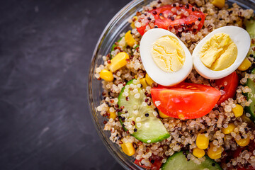 bowl of healthy quinoa with vegetables on a dark rustic background