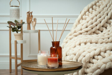 Air reed freshener and burning candles on table indoors. Interior elements
