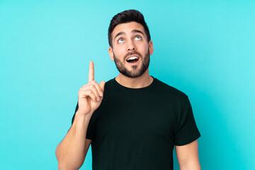 Fototapeta premium Caucasian handsome man isolated on blue background thinking an idea pointing the finger up