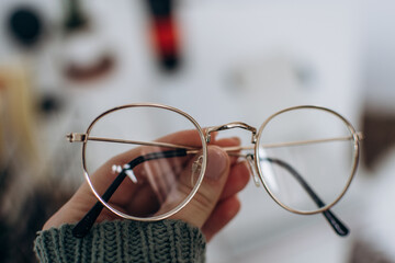 
Close-up, a woman's hand in a green sweater holds transparent glasses. Oculist, optics sale, business style