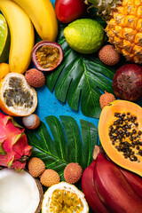 Fresh tropical fruits flat lay. Different exotic fruits on blue summer tropical background. Fresh fruits background. Travel and holiday. Healthy food, diet, vegan, vegetarian concept. Copy space