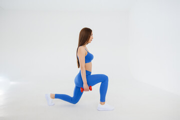 Obraz premium Sexy young girl performs sports exercises on a white background. Fitness, healthy lifestyle