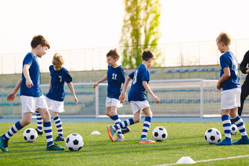 Obraz premium Football Education for Kids. Physical Education for Children. Young Coach With Kids in Soccer Team on Training Unit. Youth Team Coach Training School Boys in Football Soccer
