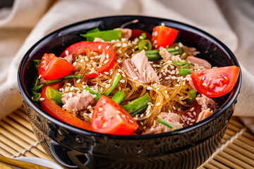 delicious glass noodles with tuna and vegetables on a dark wooden rustic background