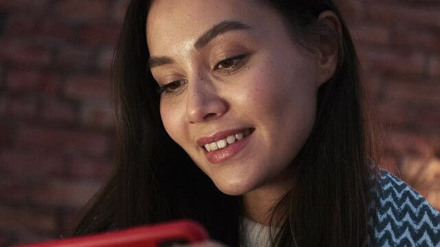 A close-up view of a happy young asian woman is using her smartphone sitting on the terrace
