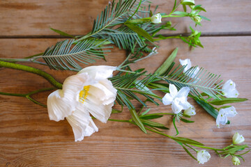 Spring white flowers with green leaves on a wooden table