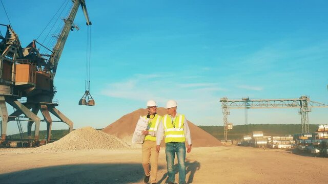 Male engineers are discussing plans in the mining zone