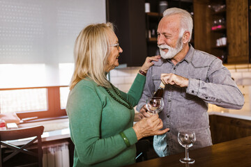 Senior couple choosing wine in the kitchen.