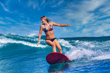 Female surfer on a blue wave at sunny day