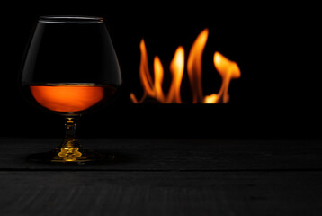 a glass of whisky with fireplace on background