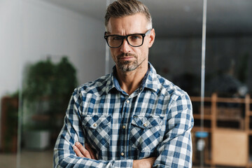 Serious white-haired man looking at camera while standing