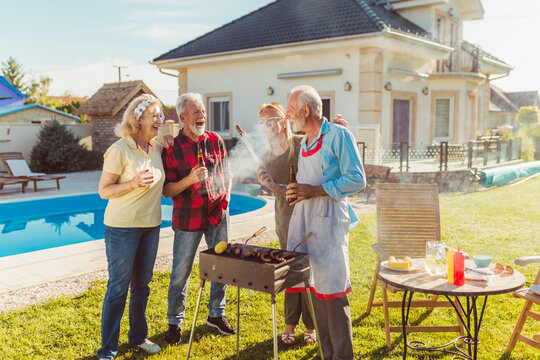 Senior friends having fun at backyard barbecue party