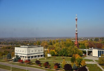 High TV tower in the distance against the blue sky. Urban autumn landscape. The post office building. Ukraine, Volnogorsk.