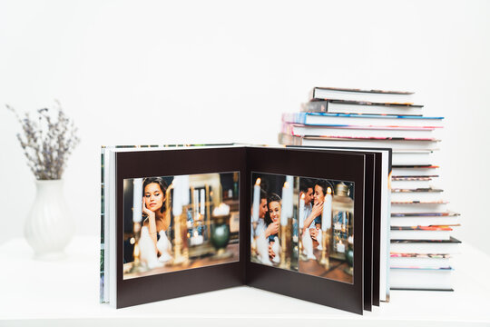 a stack of books. open photobook from photo shoots of a beautiful happy couple