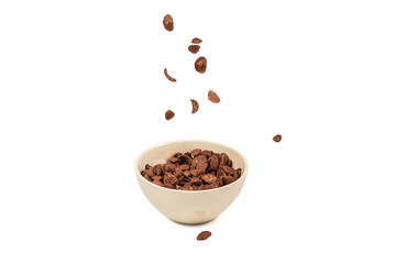 Chocolate corn flakes falling to the white bowl isolated on white. Motion.