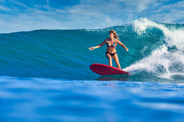 Female surfer on a blue wave at sunny day