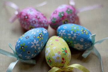 Fototapeta premium Multi-colored painted eggs with ribbons on a light background. Easter holiday