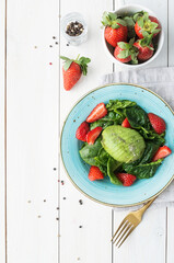 Salad with strawberries, avocados, spinach on a white wooden background top view flat lay