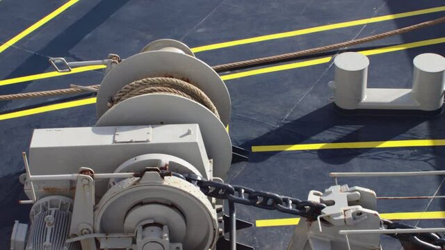 Large thick mooring rope being winched across the deck of a boat ship