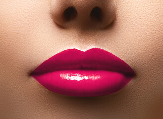 Closeup shot of beautiful full lips with magenta glossy make-up. Perfect bright pink lipstick. Plastic surgery