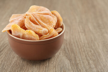 Delicious dried jackfruit slices in bowl on wooden table, closeup. Space for text