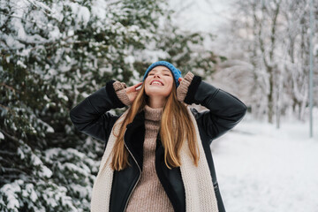 Fototapeta na wymiar Happy beautiful girl in knit hat smiling while walking in winter park