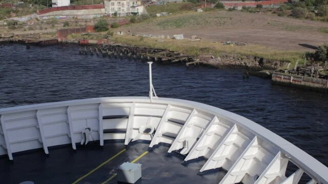 Bow of a large ship moving slowly away from it's mooring into open water